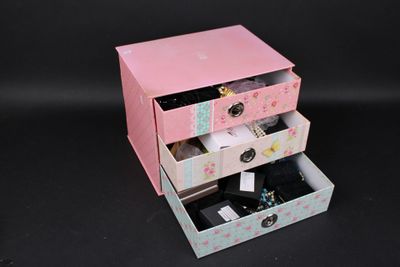 une petite commode rose avec trois tiroirs sur le dessus
