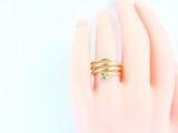 a woman ' s hand holding a gold ring with a green stone on it