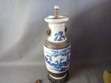 un vase bleu et blanc posé sur une table à côté d'un ventilateur