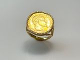a close up of a gold ring with a coin on it