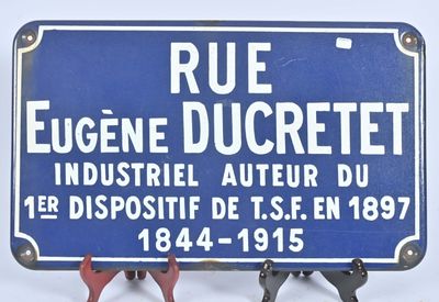 un panneau bleu indiquant « rue Eugène Ducrett, industriel et inventeur du premier dispositif de se en 1897 »