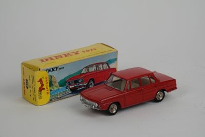 une petite voiture rouge à côté d'une boîte jaune sur une surface blanche