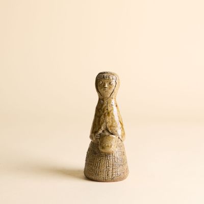 figurine en bois représentant une femme tenant un panier, posée sur une surface blanche
