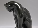 sculpture of a cat sitting on its hind legs on a white surface