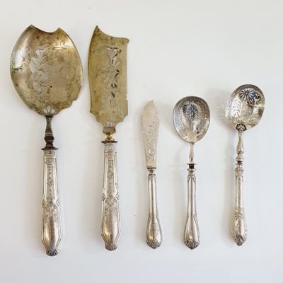 five silver spoons and two silver spoons on a white surface