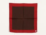 une écharpe carrée marron et rouge accrochée à un mur blanc