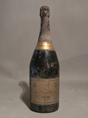an old bottle of champagne sitting on top of a white table