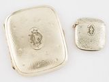 two pieces of silver jewelry sitting on top of a white surface