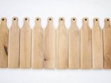 six pagaies en bois alignées sur un fond blanc