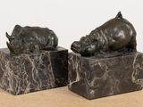pair of bronze sculptures of rhinos on marble blocks on a table