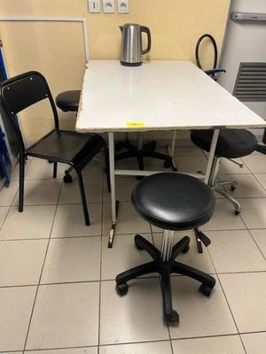 a white table with black chairs and a black stool