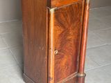 une petite armoire en bois avec un plateau en marbre, posée sur un sol carrelé