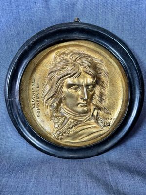 a close up of a gold medallion of a man with long hair