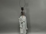 a white statue of a man with a lamp on top of a table