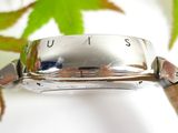a close up of a watch on a table with leaves