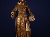 a wooden statue of a man holding a skull and a cross