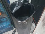 a black trash can sitting on the floor next to a book shelf
