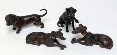 three bronze figurines of dogs and a cat on a white surface