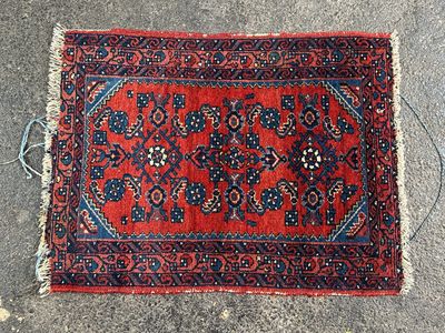 un tapis rouge bordé de bleu posé à même le sol