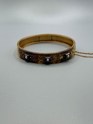 un gros plan d'un bracelet posé sur une surface blanche, avec une chaîne