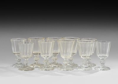 six verres à vin transparents sont alignés sur une surface blanche