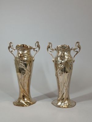 two silver vases sitting next to each other on a table