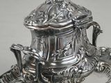 a silver plate with a silver teapot on it