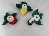 three small ceramic birds are sitting on a white surface