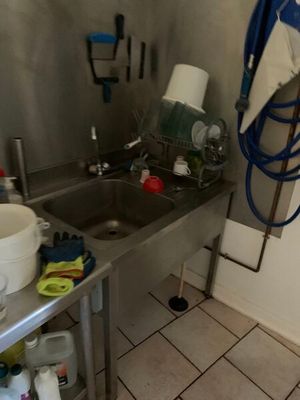 une cuisine équipée d'un évier et de nombreux produits d'entretien