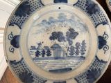 a blue and white plate with a picture of a house on it