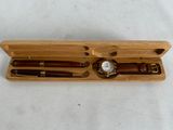 a wooden box with a watch and pen in it
