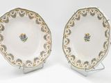two plates with gold and green designs on them on a white surface