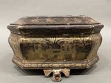 an old metal box with a painting on it sitting on top of a table