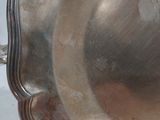 un plateau en argent muni d'une poignée, posé sur une table blanche