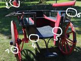 a red horse drawn carriage with numbers on it in the grass