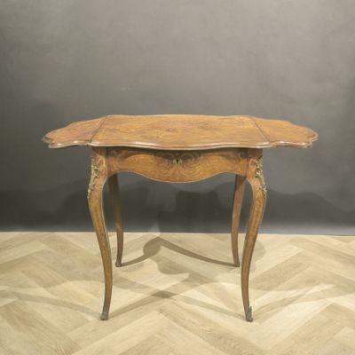 an old wooden table with a curved top on a wooden floor