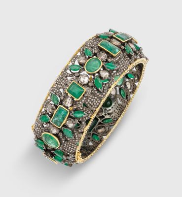 un gros plan sur un bracelet orné de pierres vertes et de diamants