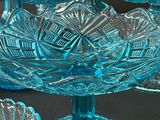 many blue glass dishes on a table with a candle