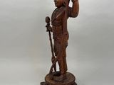 a wooden statue of a man holding a bird on his arm