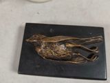 a bird statue on a marble plate next to a bowl of fruit