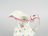 a small white pitcher with a floral design on it