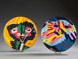 two colorful plates with faces painted on them sitting on a table