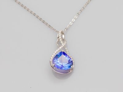 a close up of a necklace with a blue tear shaped stone on it