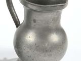 a silver pitcher sitting on a table next to a white background