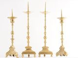 trois chandeliers dorés posés les uns à côté des autres sur une surface blanche