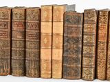 several old books are lined up in a row on a white surface