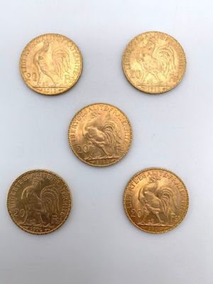 cinq pièces d'or présentant des motifs différents, posées sur un fond blanc