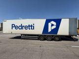 La semi-remorque est garée sur un parking et porte un logo bleu et blanc sur le côté.