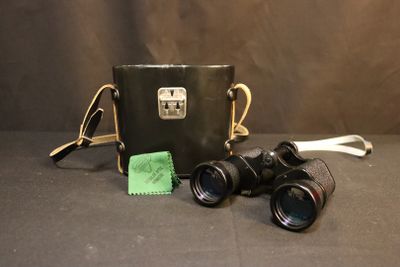 an old pair of binoculars and a cloth are on a table
