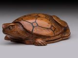 une image représentant une figurine de tortue en bois posée sur une surface grise
